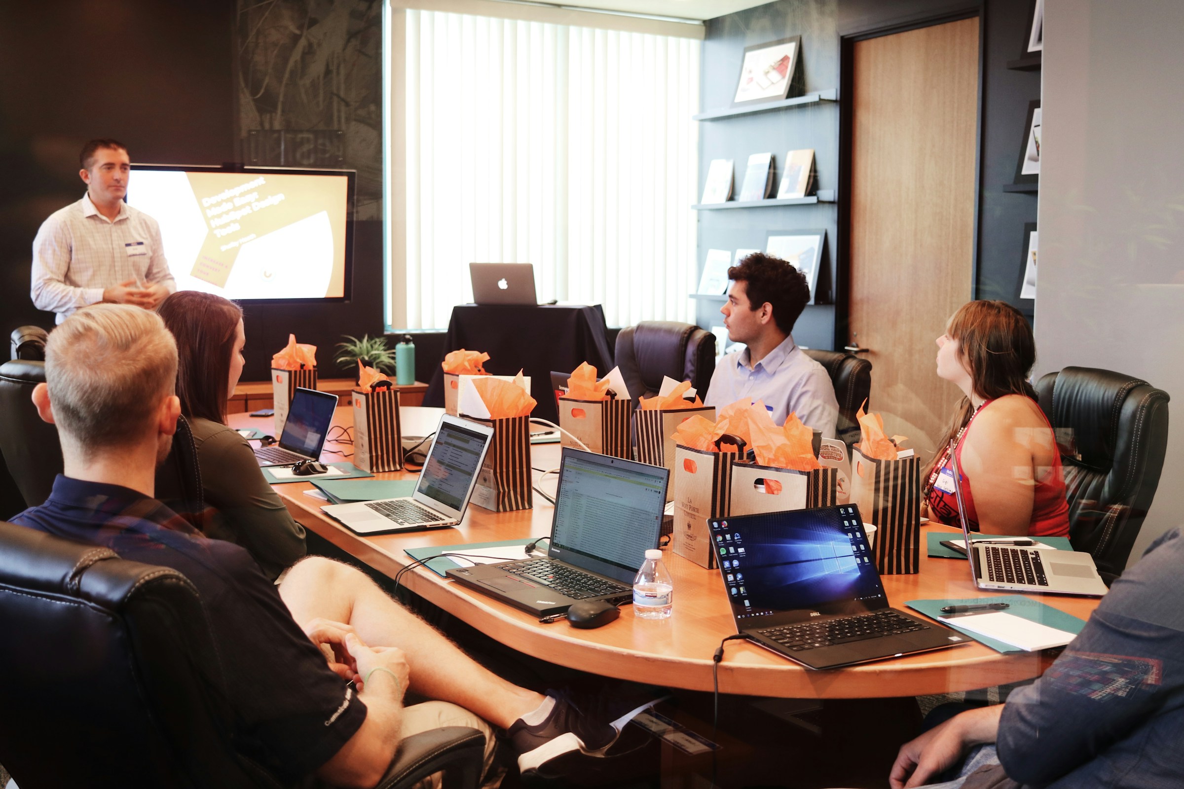 A diverse team engaged in a discussion in a conference room with laptops and documents.
