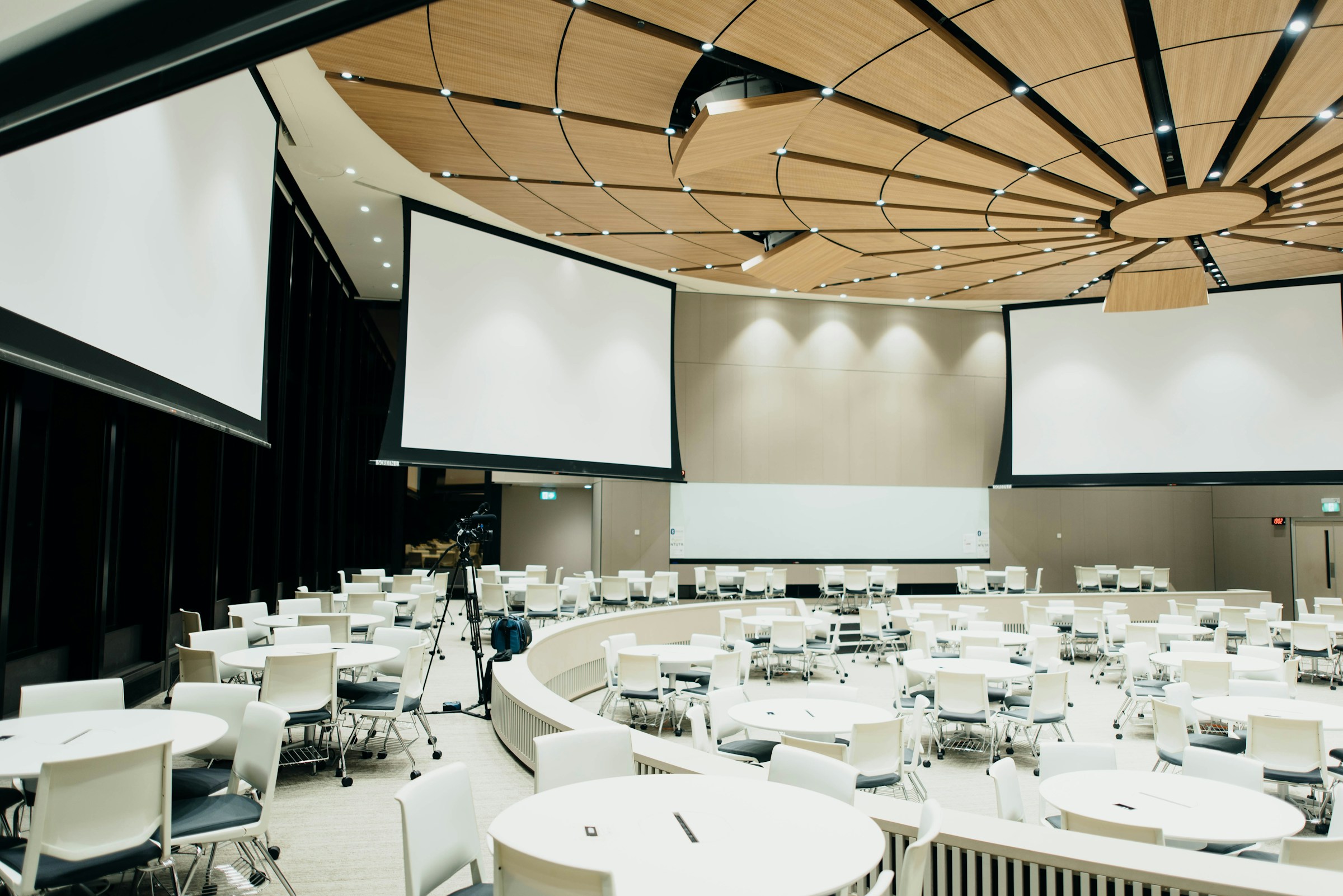 A spacious conference room with white tables and chairs, ready for corporate meetings and events.