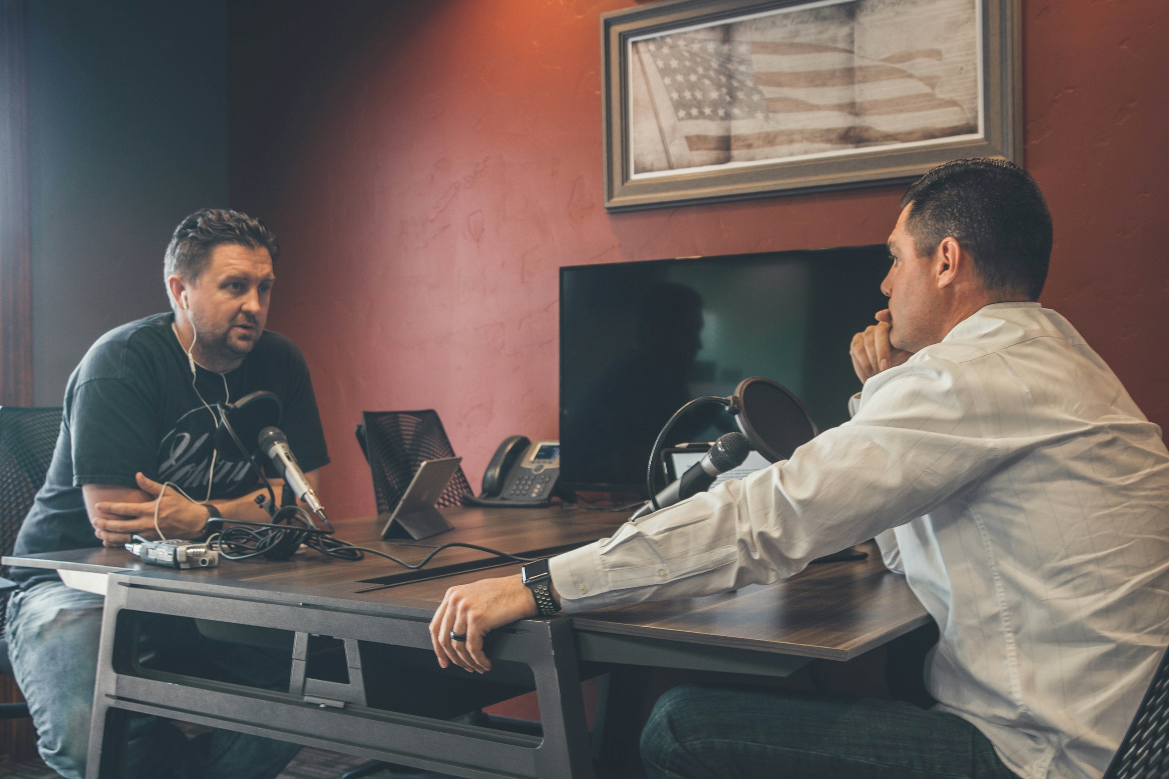 A professional meeting in a conference room where people are seated at a table with microphones.