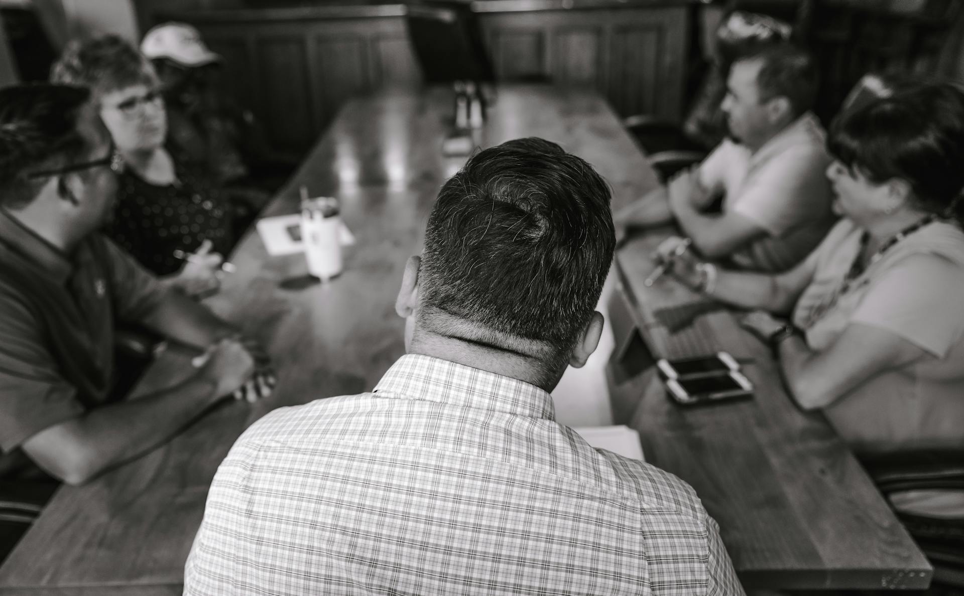 A professional meeting in a conference room with a long table and engaged participants.