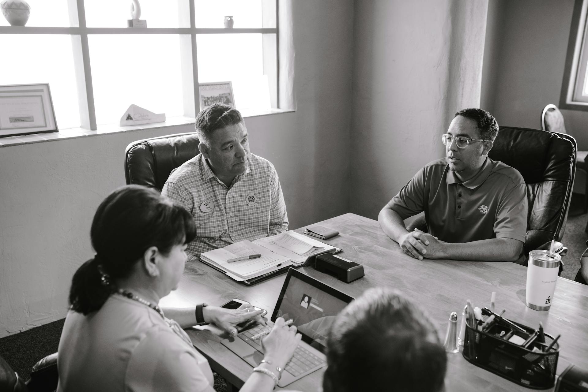 Business professionals seated around a table in a conference room, discussing ideas.